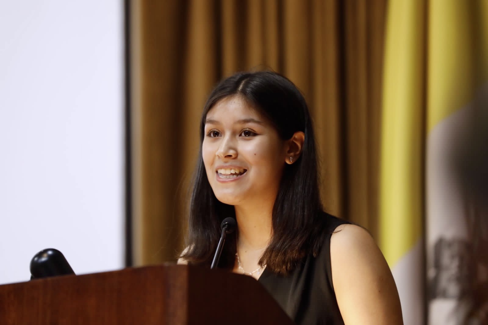 Estudiante del Programa Penta UC de la Academia de Desarrollo de Talentos UC Rolando Chuaqui, dando un discurso en un podium durante la Ceremonia de Egreso 2023 del programa. Derechos de imagen pertenecen a Penta UC.