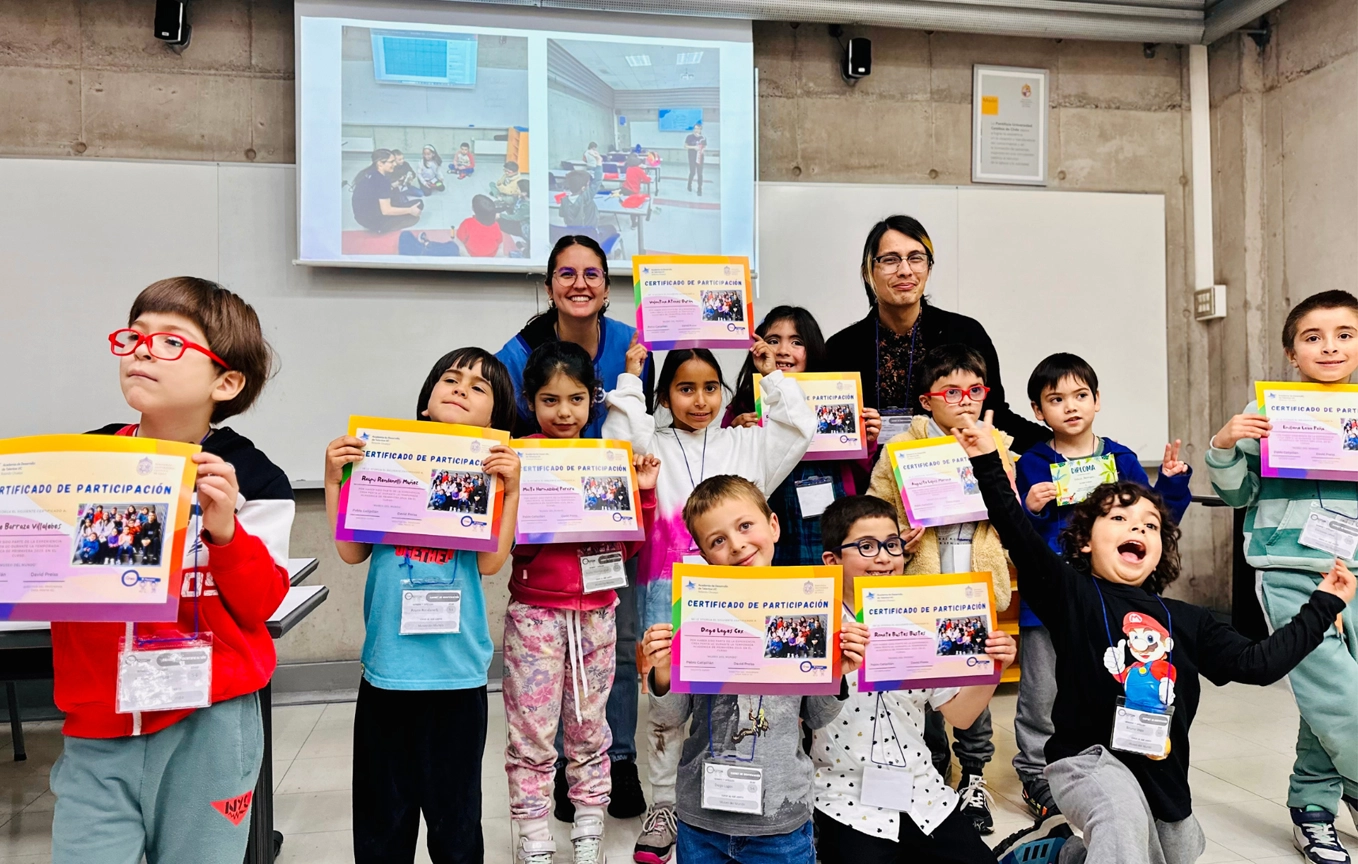 Estudiantes del programa CREA de la Academia de Desarrollo de Talentos UC Rolando Chuaqui, sosteniendo sus diplomas en el día de su graduación, junto a su docente y ayudante. Derechos de imagen pertenecen a Penta UC.